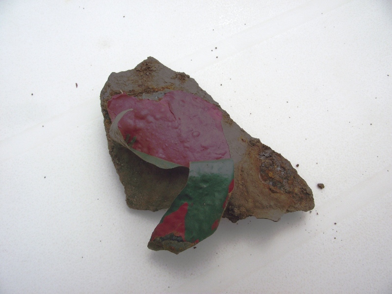 This was identified as Iron, which it certainly seems to be. Possibly a piece of old guttering, with two very distinct coats of paint on it.